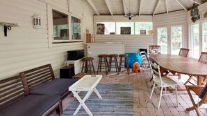 A rustic cabin interior with a wooden dining table, bar stools, a sofa, and a kitchen area. - 2 bedroom cozy home in Sösdala (Sösdala)