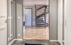Ein Flur mit einer Holztreppe, einer Tür und einem Lichtschalter an der Wand.
