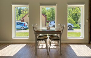 A dining area with a table and chairs, large windows with a view of parked cars and greenery outside. - Awesome home in Reftele with WiFi (Reftele)