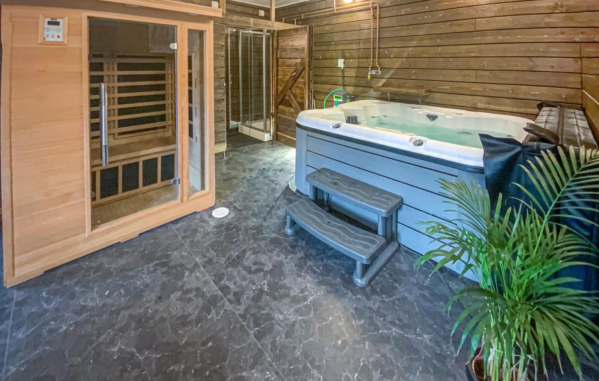 Una stanza spa con vasca idromassaggio, sauna in legno e un piccolo gradino che conduce alla vasca.
