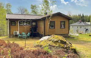 A wooden cabin with a porch, outdoor seating, and a large rock with moss. - 3 bedroom beautiful home in Sjötofta (Sjötofta)