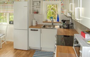 Una cocina compacta con refrigerador, lavavajillas y ventana con vista a la vegetación.