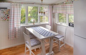 Una cocina con una mesa a cuadros, sillas a rayas y un ventanal con cortinas.