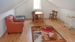 Une pièce de style loft avec une table à manger en bois, deux chaises en bois, un canapé en cuir rouge, un petit canapé gris et un tapis coloré.