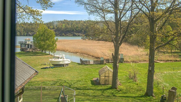 Un bateau est amarré près d’un lac, avec une maison et un petit abri de jardin en premier plan.