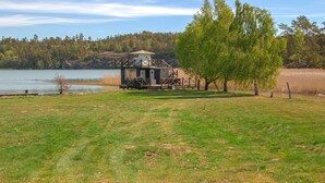 Une cabane dotée d’une terrasse, entourée d’un champ verdoyant et d’un lac.