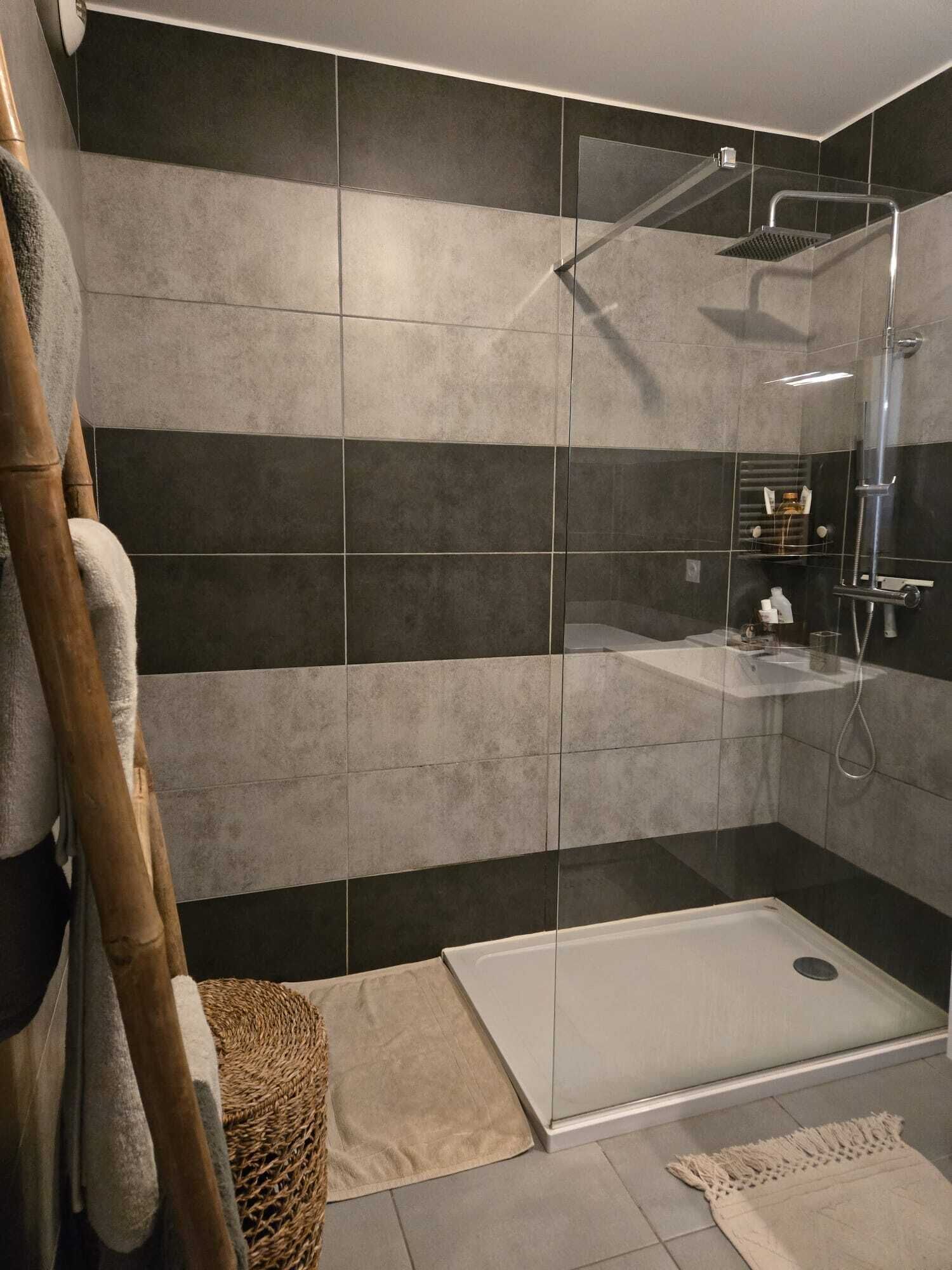 A modern bathroom with a glass shower enclosure, a white bathtub, and a separate shower area.