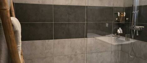 A modern bathroom with a glass shower enclosure, a white bathtub, and a separate shower area.