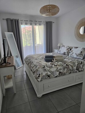 Ein Schlafzimmer mit einem Bett, einem Nachttisch, einem Spiegel und einer Deckenleuchte.