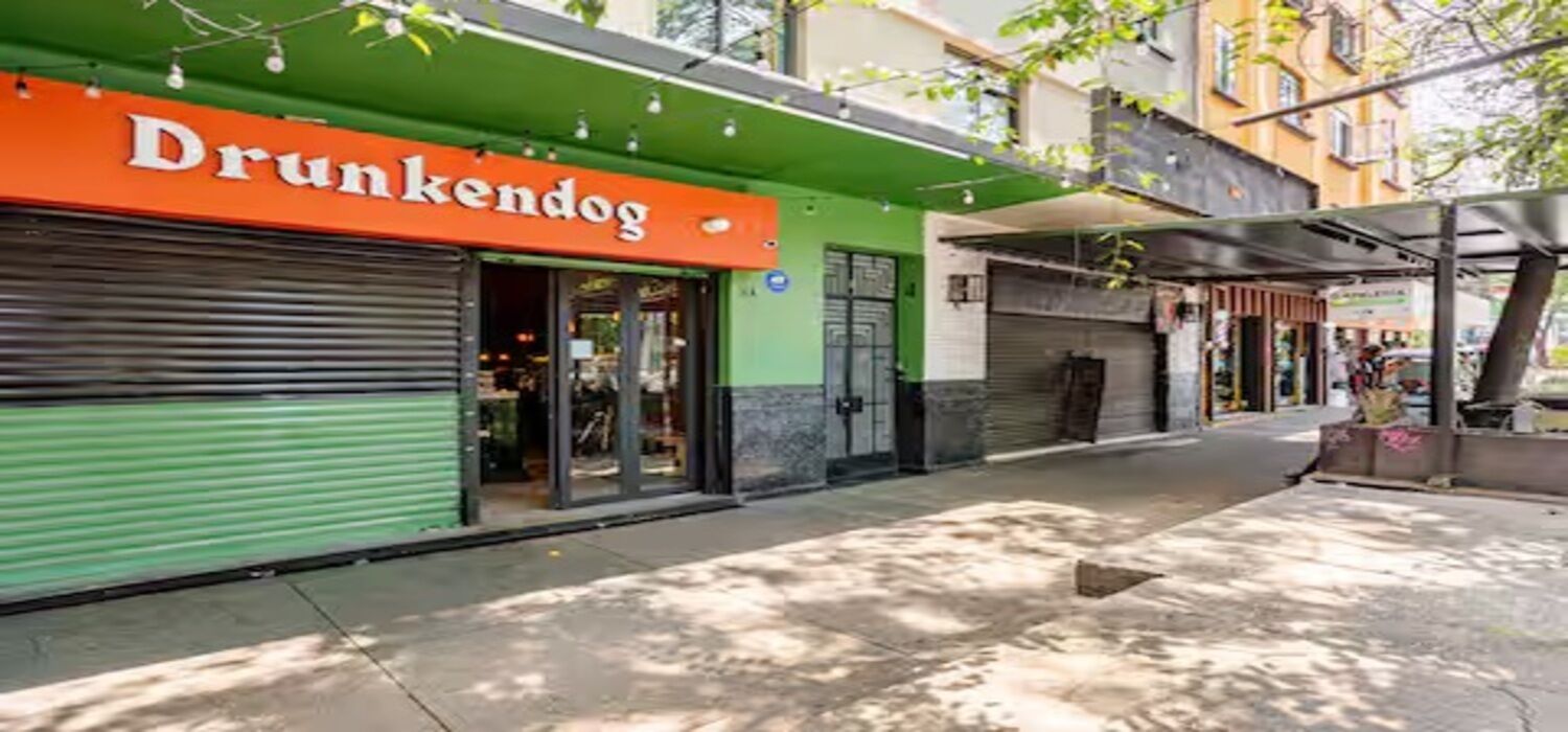 Ein Schaufenster mit einer grünen Markise und einem orangenen Schild, auf dem 'Drunkendog' steht.