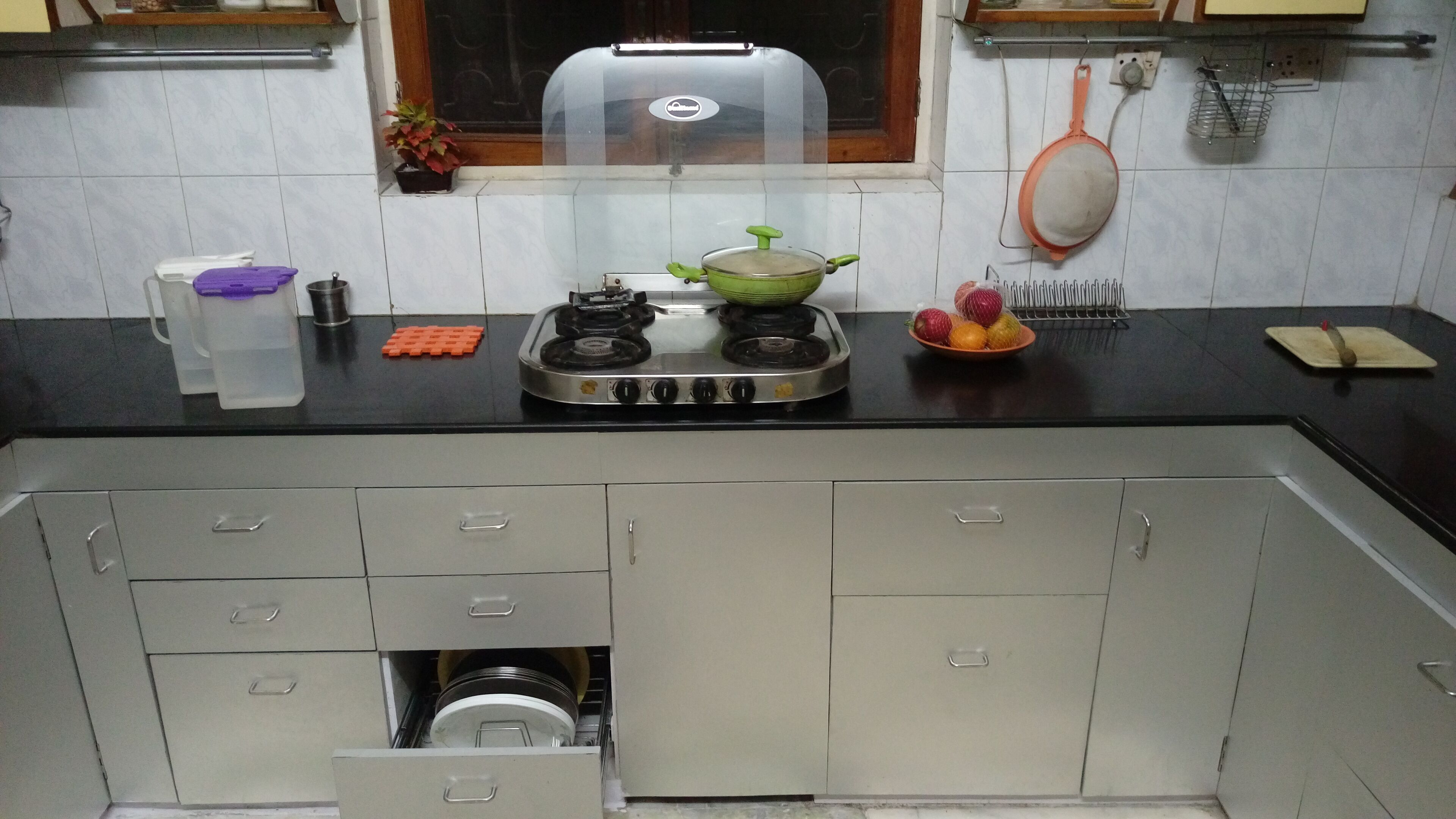Una cocina con estufa a gas, pileta, alacenas y ventana.