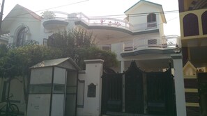 A multi-story building with balconies, a gated entrance, and a sign indicating the address. - Fabulous 2-bedroom bungalow with AC in charming Lucknow Gomtinagar (Lucknow)