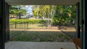 Een open terras met uitzicht op een aangelegde tuin, inclusief bomen en een gebouw op de achtergrond.