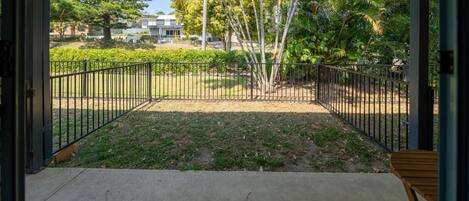 Un pati obert amb vista a una zona enjardinada, incloent arbres i un edifici al fons.