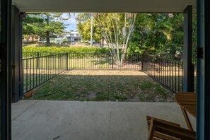 An open patio with a view of a landscaped area, including trees and a building in the background. - Woolgoolga Coast Motel (Woolgoolga)