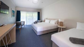 A hotel room with a bed, a desk, a chair, and a small table.