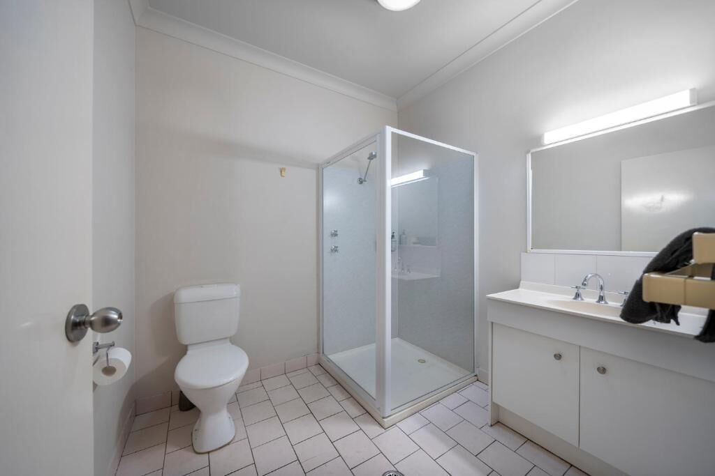 Un baño con inodoro, cabina de ducha y lavabo con espejo.