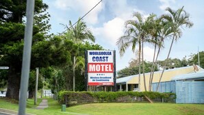 Een motelbord met een groot bord, een gebouw met een blauw dak en omliggend groen.