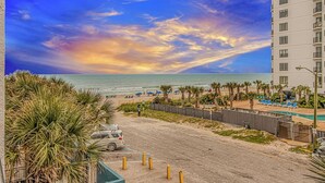 Vista de la playa con un hotel, una piscina y un atardecer.