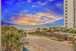 Blick auf einen Strand mit Hotel, Schwimmbad und Sonnenuntergang.