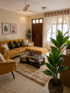 A living room with a sofa, coffee table, and potted plants. - Maisha Garden  (Dar es Salaam)