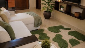 A room with a sofa, a television, a potted plant, and a door. - Maisha Garden  (Dar es Salaam)