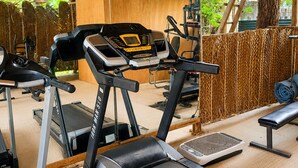 Un gimnasio con cintas de correr, una banca y techo de madera.