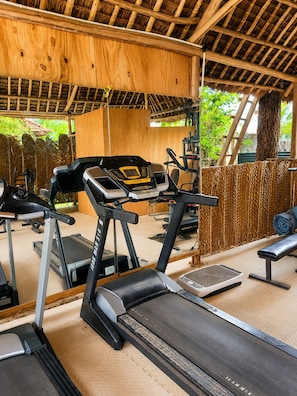 Un gimnasio con cintas de correr, un banco y equipo de ejercicio.