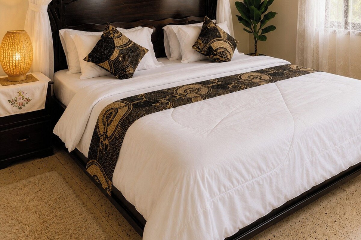 A bed with a canopy, white bedding, and patterned pillows.