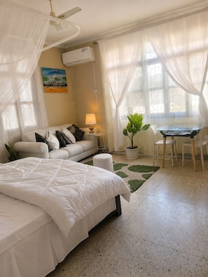 Un dormitorio con cama, sofá, mesa y una planta en maceta.