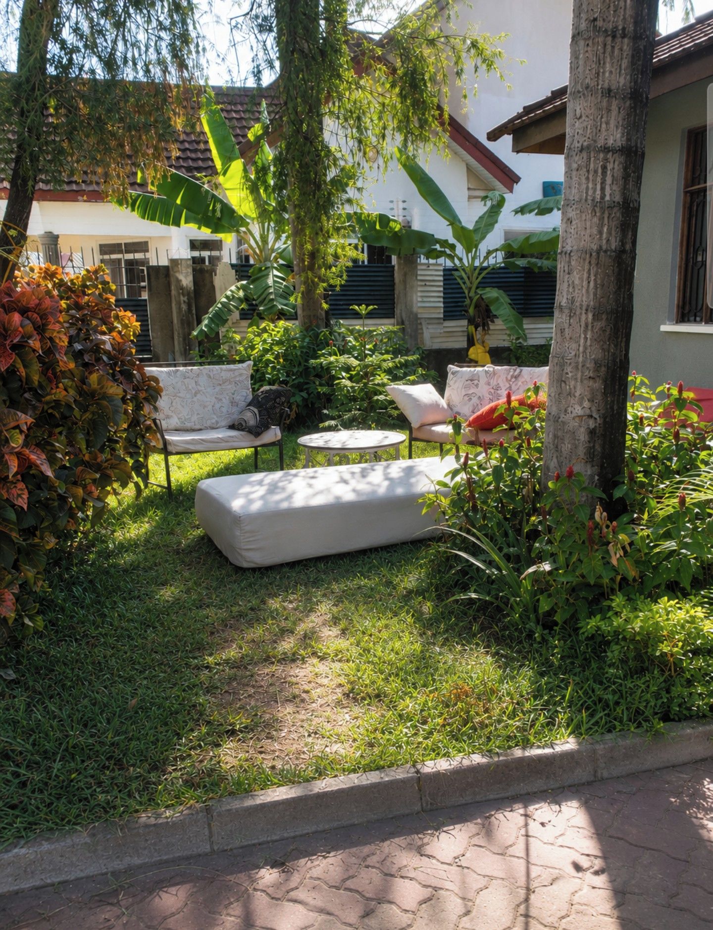Eine Terrassenfläche mit Gartenmöbeln, darunter eine Sitzecke mit Sofa und Stühlen, umgeben von Pflanzen und einem Baum.