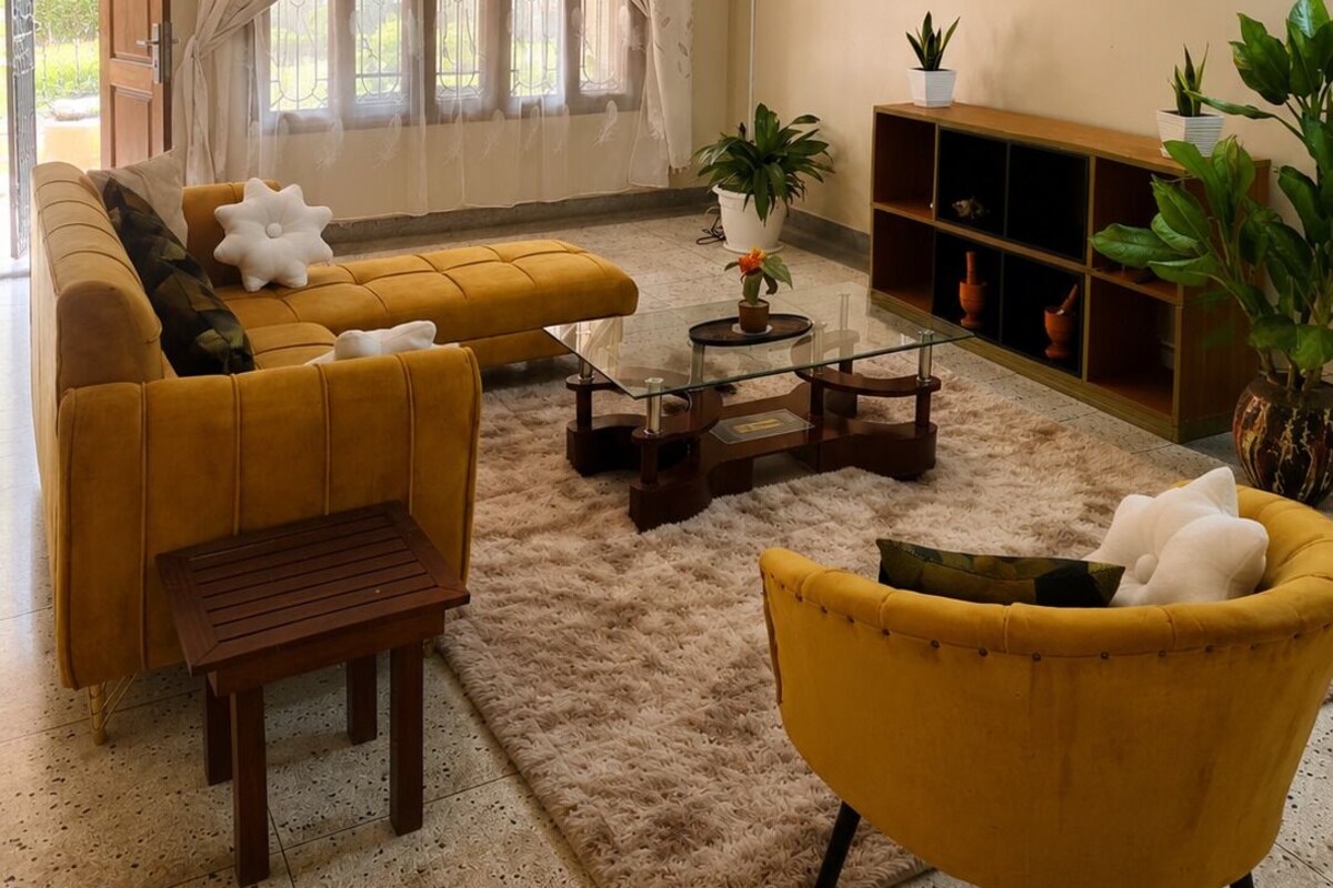 A living room with a sofa, armchair, coffee table, and a bookshelf.