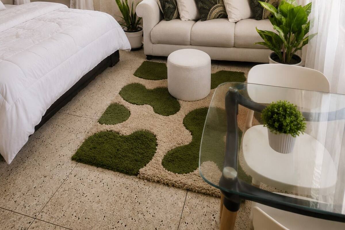 Un dormitorio con una cama, un sofá, una mesa de vidrio y una planta en maceta.