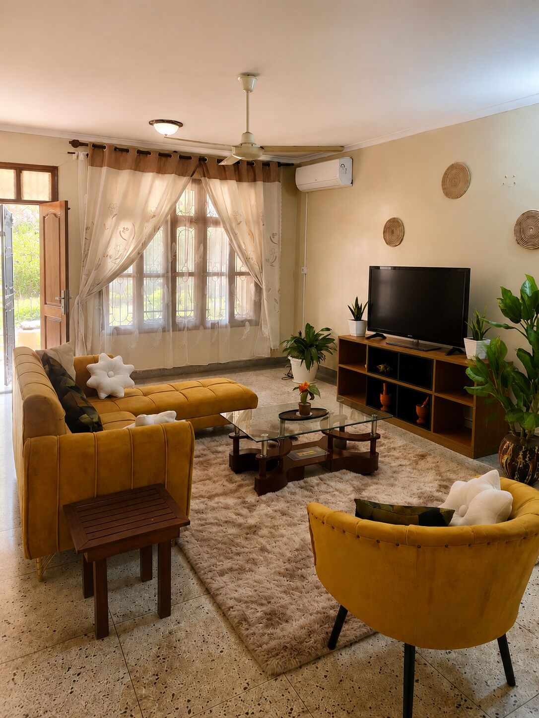 Una sala de estar con sofá, sillón, mesa de centro, televisor y objetos decorativos.