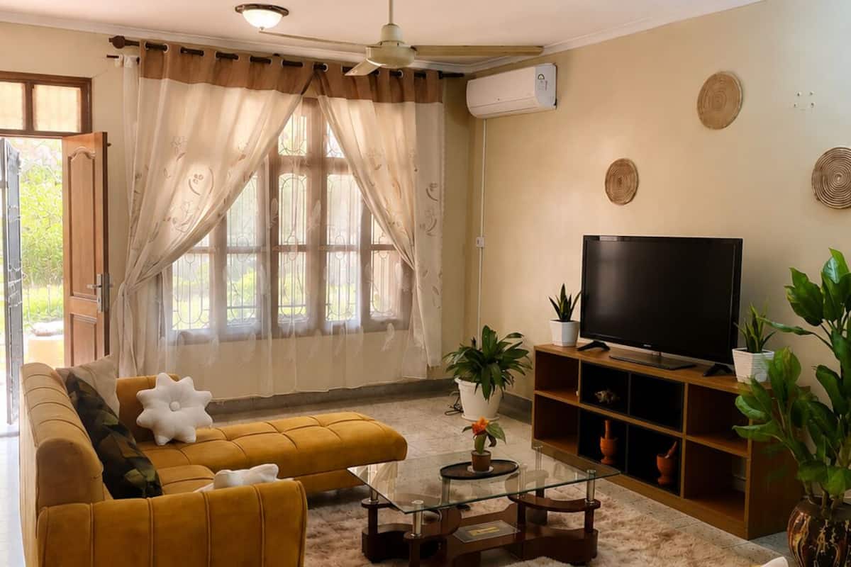 A living room with a sofa, armchair, coffee table, TV, and decorative items.