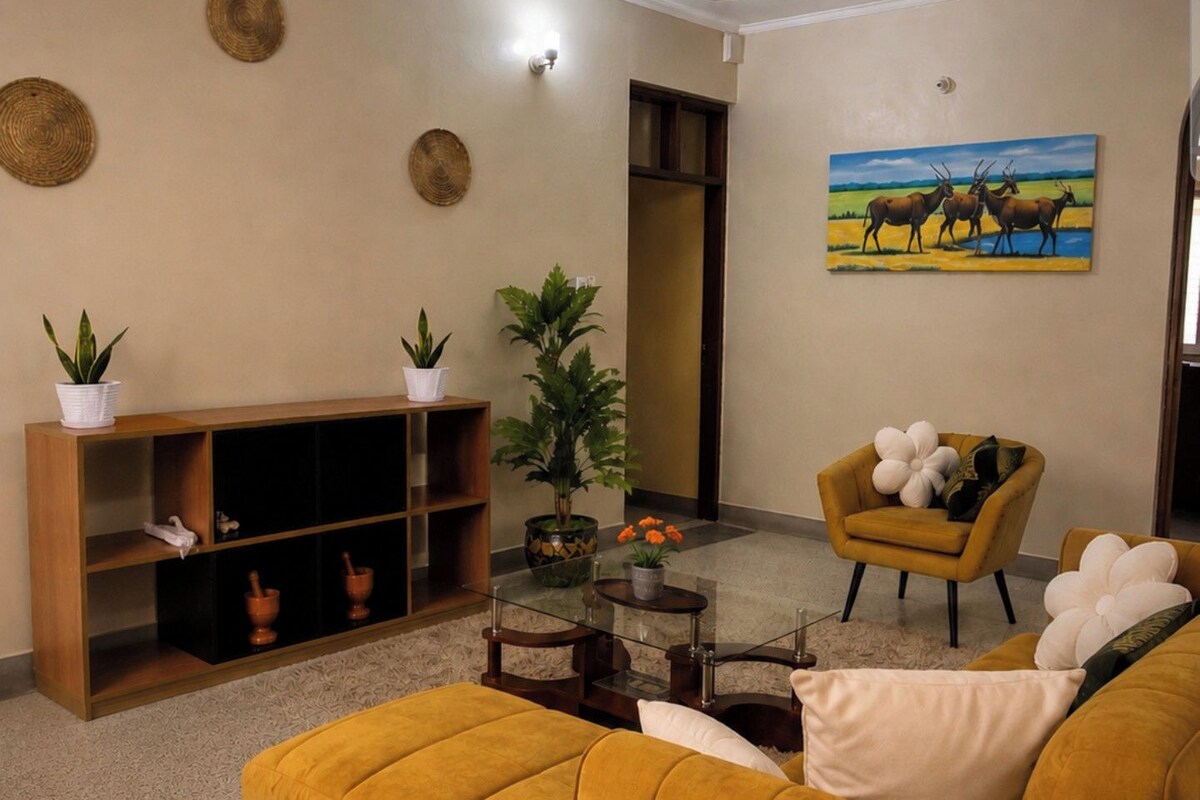 A living room with a yellow sofa, a wooden cabinet, a painting, and a ceiling fan.