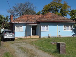 Un bâtiment d’un seul étage, avec un toit recouvert de tuiles rouges, une façade bleue et le chiffre « 20 » bien visible sur le devant.