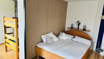 Une chambre moderne avec un lit en bois, une échelle en bois et un panneau mural à rayures.