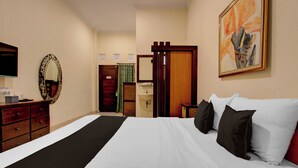 A hotel room with a bed, dresser, mirror, artwork, and a door leading to a bathroom. - Townhouse Oak Pancanaka Malioboro Hotel (Kasihan)