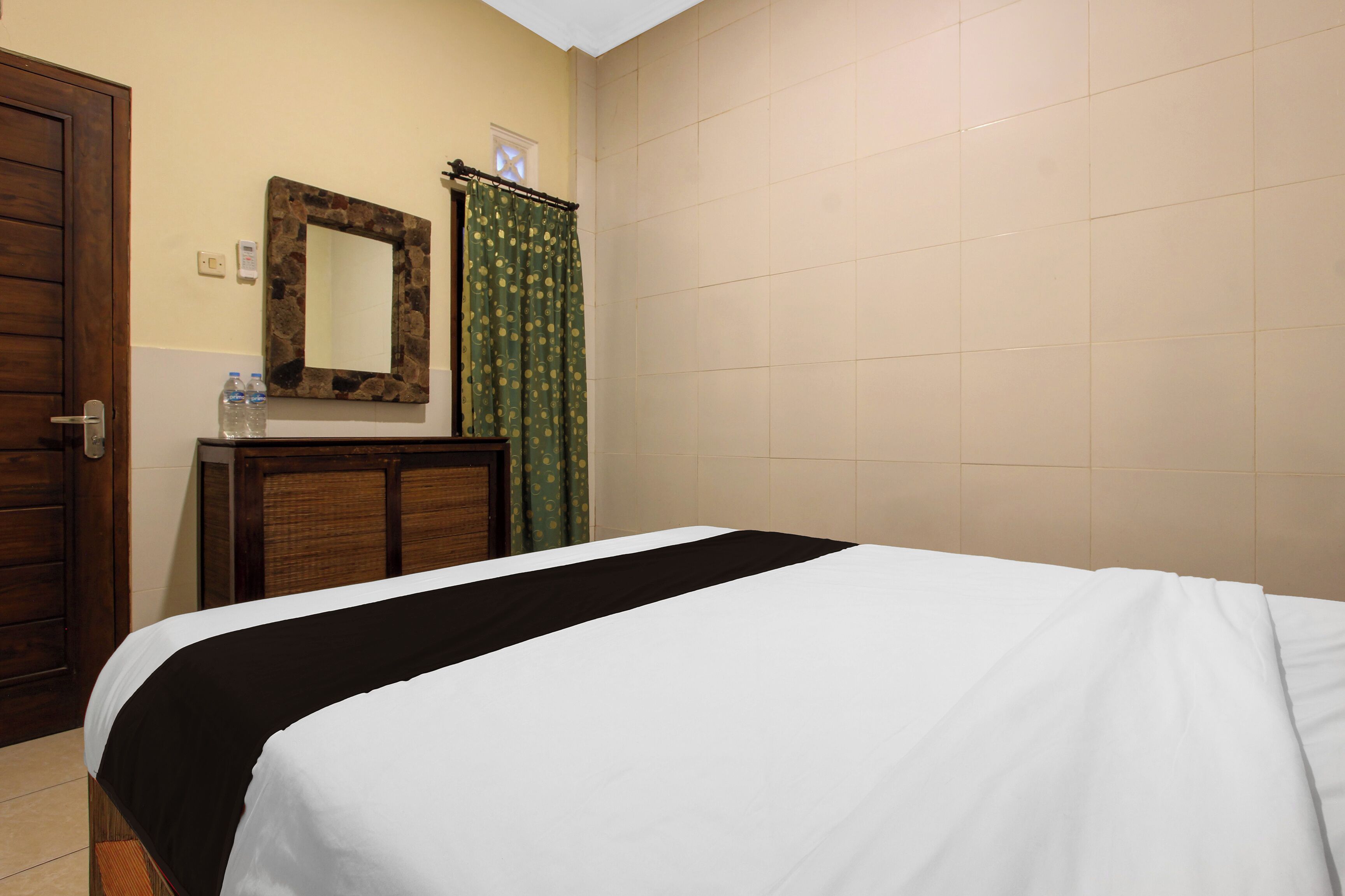 Een hotelkamer met een bed, een houten dressoir, een spiegel en een douchegordijn.