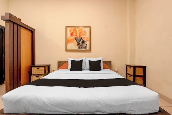 Une chambre d’hôtel avec un grand lit, une armoire en bois, un tableau accroché au mur et deux tables de chevet avec des paniers.