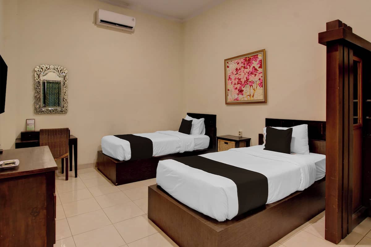 A hotel room with two beds, a desk, a chair, a mirror, and a painting on the wall.