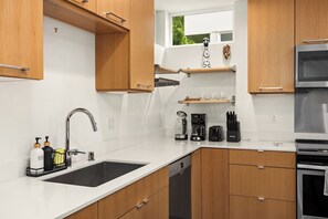 Een moderne keuken met houten kastjes, een roestvrijstalen spoelbak, een vaatwasser, een koffiezetapparaat en een broodrooster.