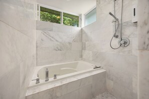 Een moderne badkamer met een marmeren douche, een badkuip en een raam voor natuurlijk licht.