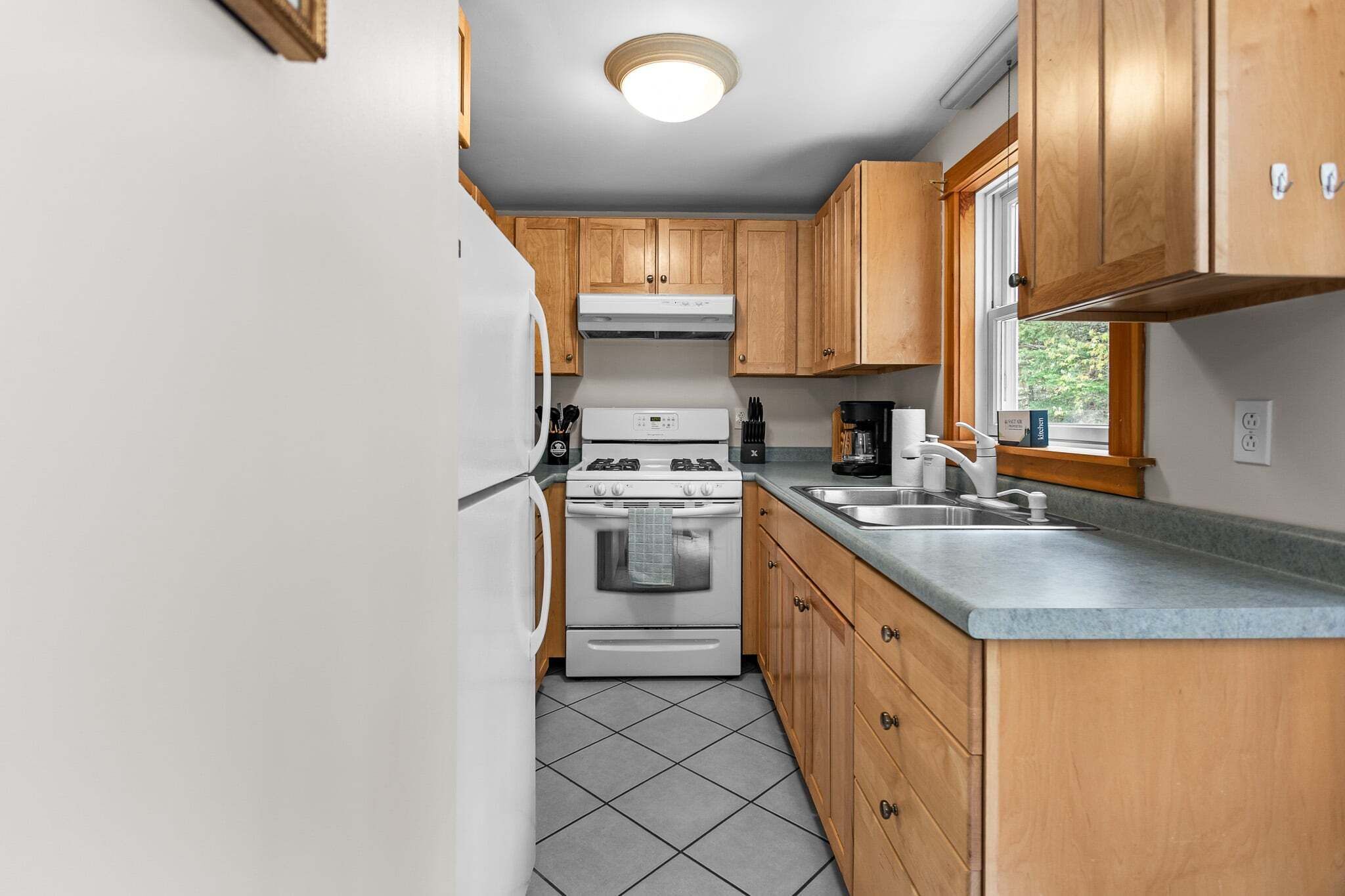 A compact kitchen with wooden cabinets, a white stove, and a sink.