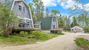 En enkel stuga med en grusväg som leder fram till den, omgiven av träd och grönska.