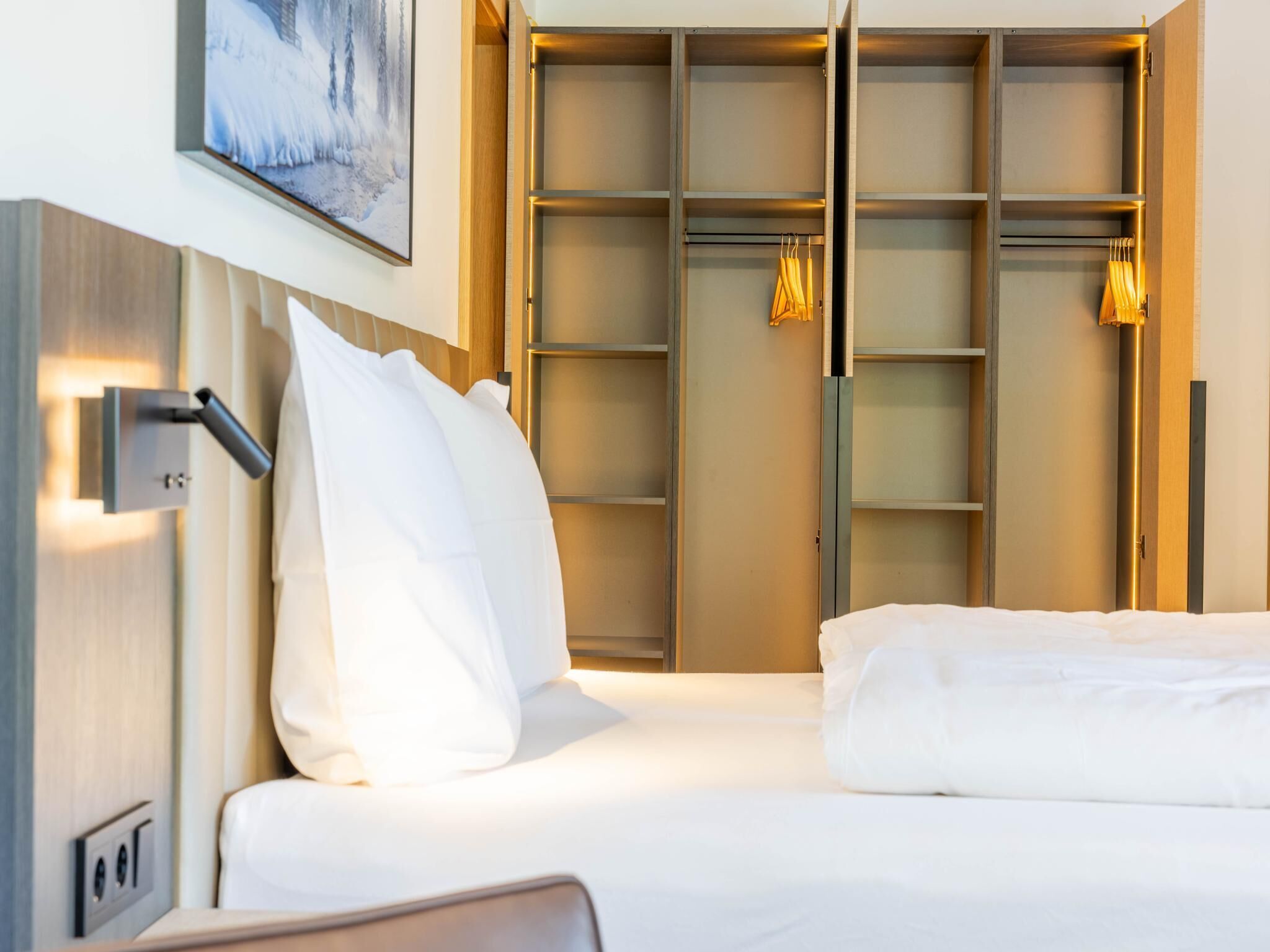 Una habitación de hotel con cama, armario y un cuadro en la pared.