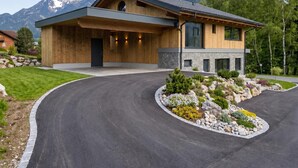 A modern house with a stone facade, a wooden deck, and a landscaped driveway.