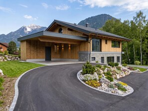 A modern house with a stone facade, a wooden deck, and a landscaped driveway.