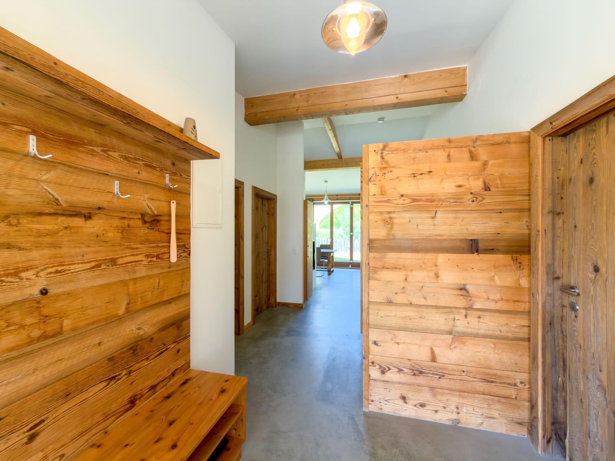 A wooden interior hallway with a bench, wooden walls, and a ceiling light.